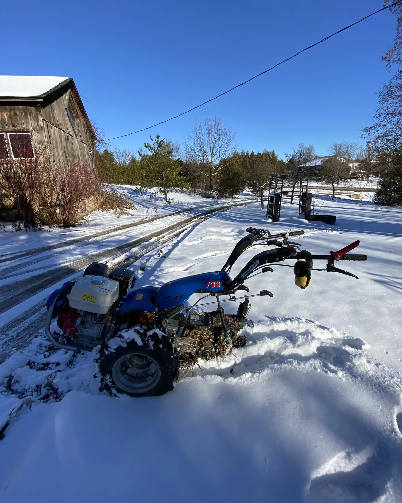 The trencher in fresh snow beside a barn
