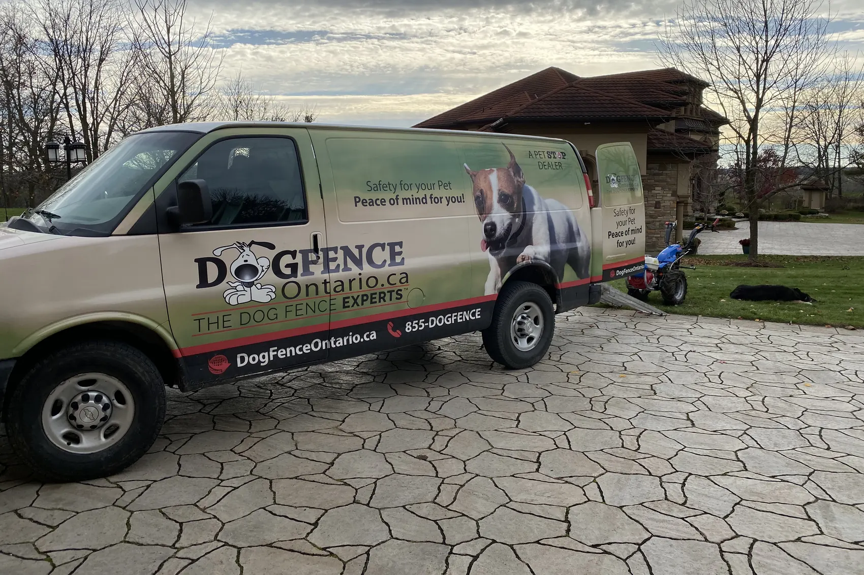 The Dog Fence Ontario van on a flagstone driveway with the trencher unloaded beside it
